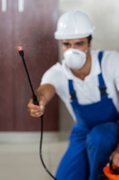 Manual worker spraying insecticide in kitchen