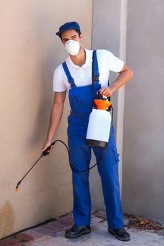 Portrait of worker spraying chemical on wall