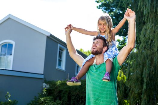 Father carry daughter on shoulders in yard
