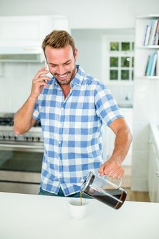 Man pouring coffee while talking on cellphone