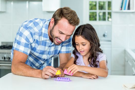 Father and daughter playing with toy block at table