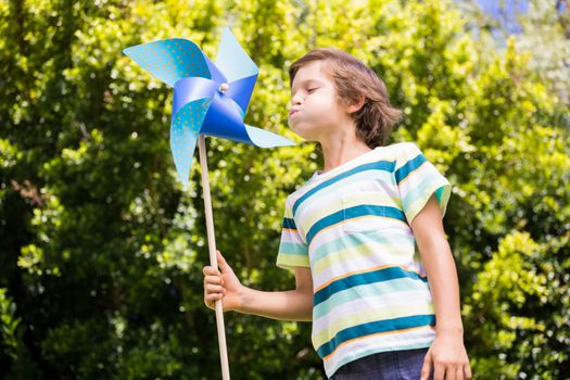 A little boy is blowing on pinwheel