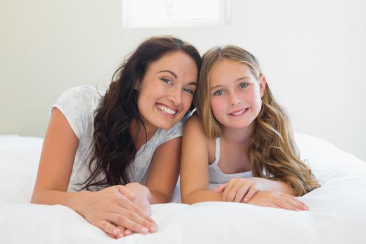 Mother with cute daughter lying in bed
