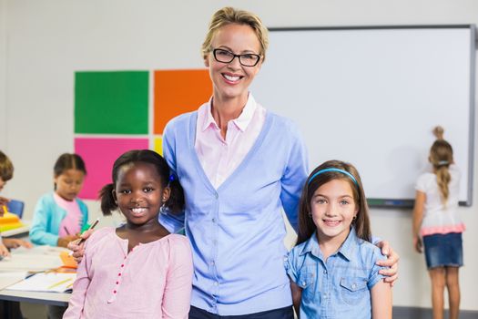 Portrait of smiling teacher and kids standing together with arm around