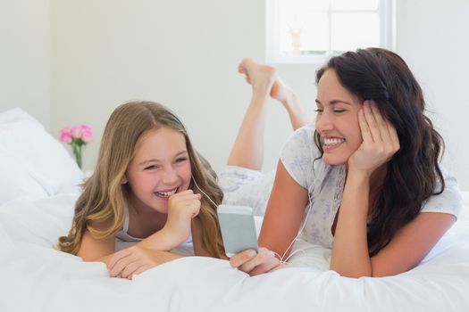 Mother and daughter listening to music in bed