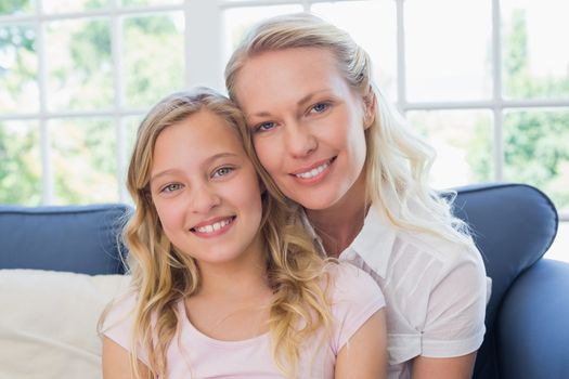Happy mother and daughter sitting on sofa