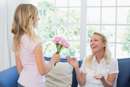 Girl giving flower bouquet to surprised mother
