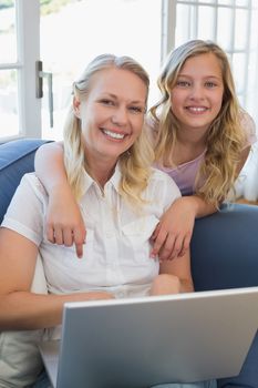 Happy mother and daughter with laptop in house
