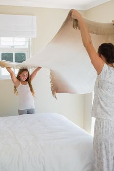 Mother and daughter making bed