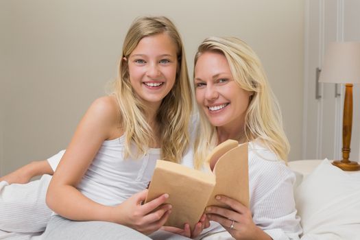 Mother and daughter holding story book in bed