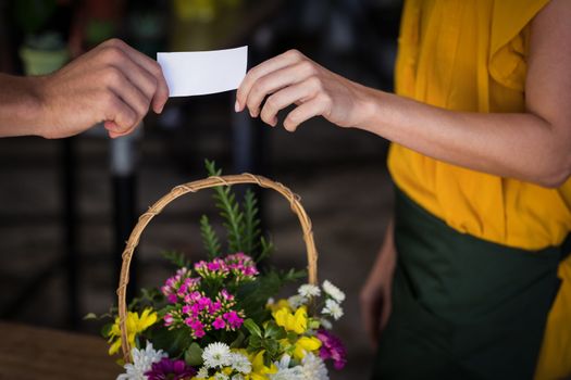 Female florist giving visiting card to customer