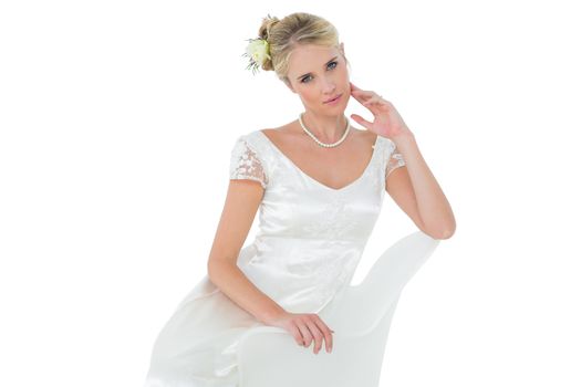 Sensuous bride sitting on chair over white background