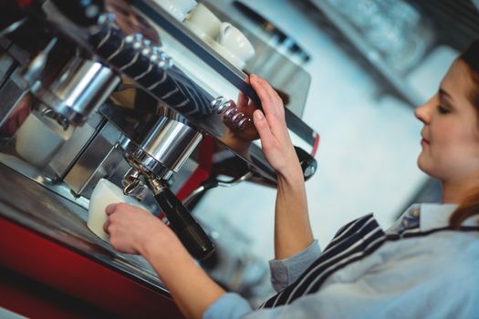 Tilt shot of barista using espresso machine to pour coffee in cup