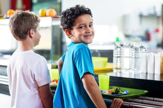 Schoolboy with classmate standing near canteen counter