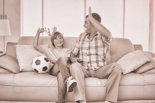 Father and son giving high-five while watching soccer match