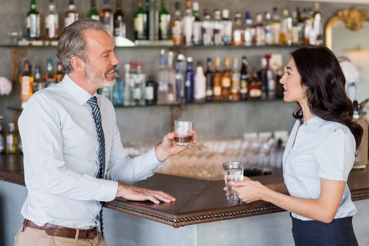 Businessman and woman standing at bar counter having drink in restaurant