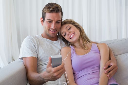 Couple listening music with mobile phone on couch