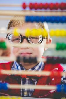 Close-up of schoolkid looking through abacus in classroom