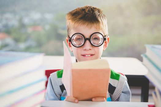 Portrait of schoolkid reading book in classroom