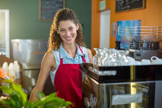 Portrait of smiling female staff standing at coffee shop counter