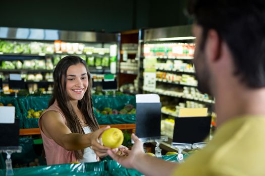 Woman giving fruit to cashier for billing at supermarket