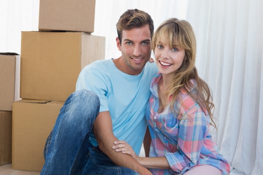 Couple sitting against cardboard boxes in new house