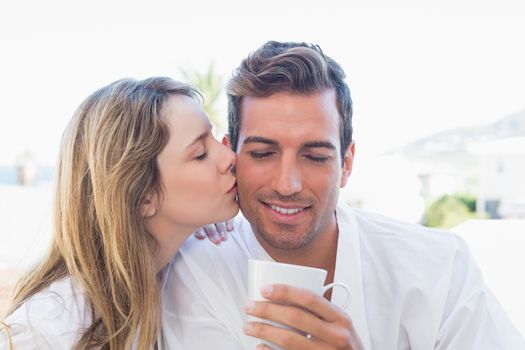Woman kissing man while having coffee
