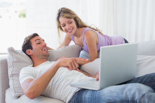 Relaxed loving couple with laptop on couch