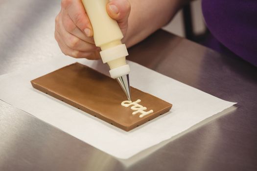 Worker writing happy birthday with piping bag on chocolate plaque