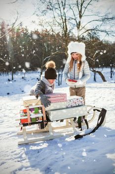Composite image of brother and sister keeping presents on sled