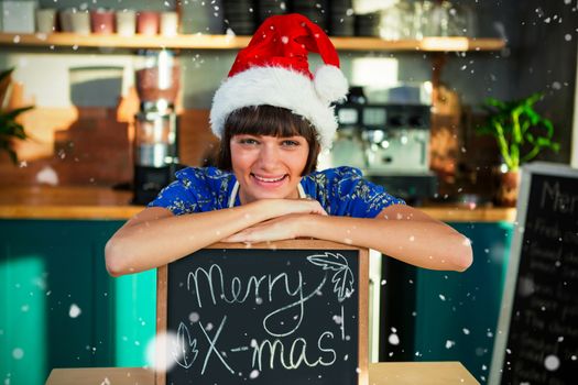 Composite image of portrait of smiling waitress wearing santa hat and sitting with x-mas sign board