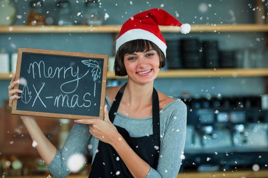 Composite image of portrait of waitress showing slate with merry x-mas text