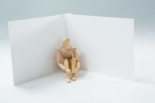 Wooden figurine sitting against wall
