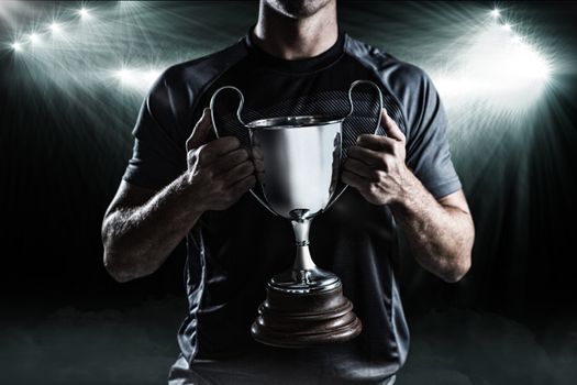 Composite image 3D of victorious rugby player holding trophy