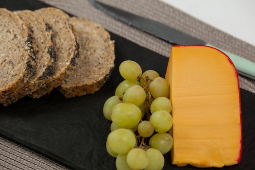 Brown bread, grapes and gouda cheese on slate board