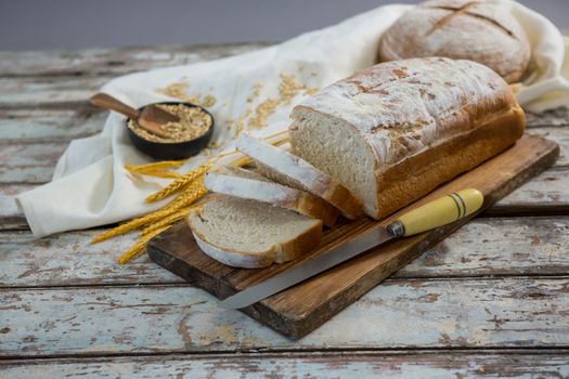 Bread loaf with knife, wheat grains and oats
