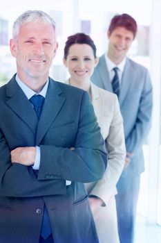 Smiling mature businessman standing upright in front of his young team