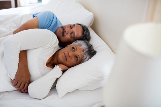 Senior couple relaxing together on bed in bedroom