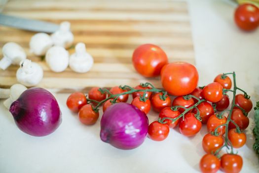 Cherry tomatos, onions and mushrooms on kitchen worktop
