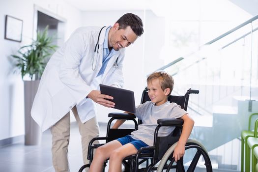 Smiling doctor showing digital tablet to disable boy