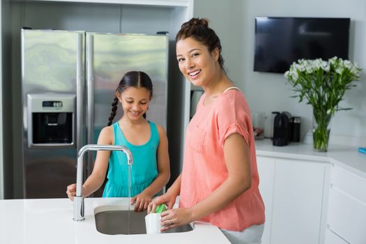 Mother assisting her daughter in cleaning vessel