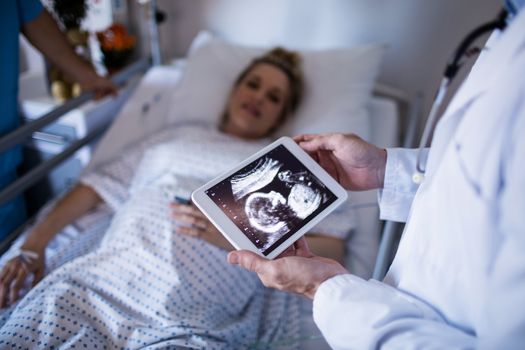Male doctor looking at sonography report on a digital tablet
