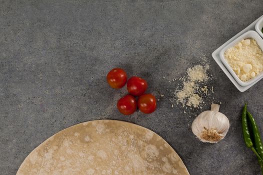 Pizza dough and ingredient on grey background