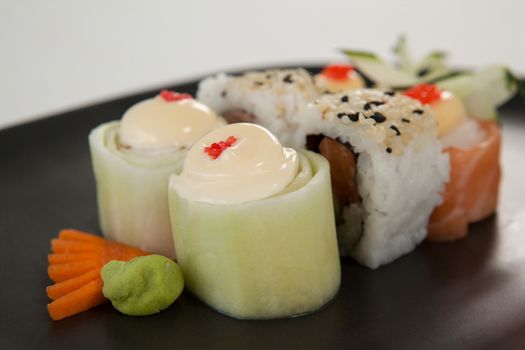 Uramaki and nigiri sushi served in black plate against white background
