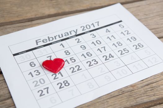 Red heart shape placed on 14th february date of the calendar