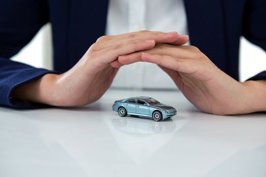 Businesswoman protecting toy car with hands