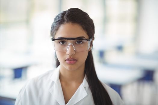 Portrait of schoolgirl wearing protective eyewear in laboratory