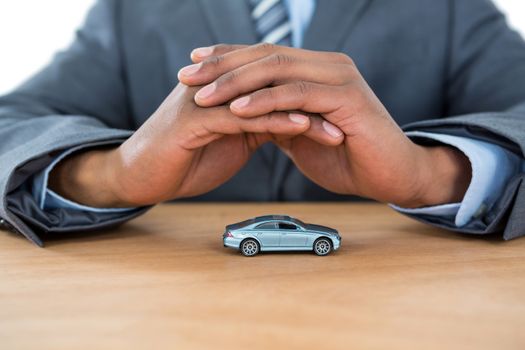 Businessman protecting toy car with hands
