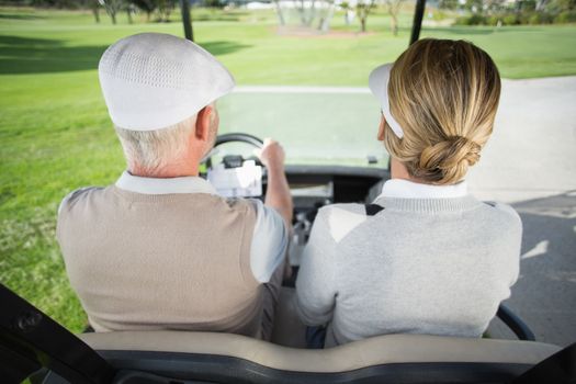 Golfing couple driving in their golf buggy