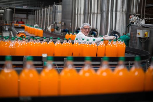 Factory engineer monitoring filled juice bottle on production line